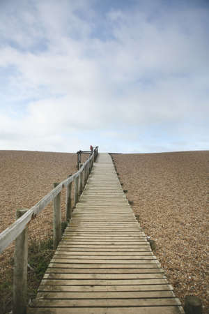 A wooden path to the beach over small pebblesの写真素材