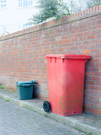 A red and green bin resting against a wall.の写真素材