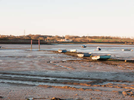 A wonderful shot of the river and its bank with the tide out on a clear day with boatsの写真素材