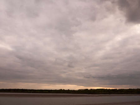 Low tide summer sky nightfall grey clouds mood and reds with river running through in wivenhoe essex...