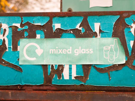 a green recycling sign near glass recycle plant and bins saying mixed glass with pictures of jars and bottles environment cleanの写真素材
