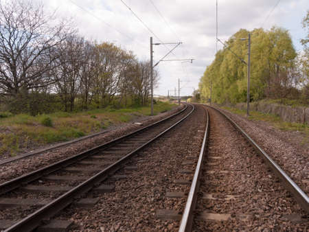 Wonderful shots of day time train tracks as seen standing on the track, no people, no train, in the countryside and forest with trees and plants and safety signs in day time light in summerの写真素材