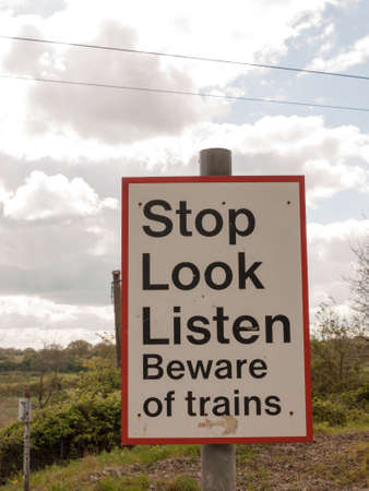 A Railway Safety Sign Saying Stop Look Listen Beware of Train Red and White and Black and on a Pole in the Country in Springの写真素材