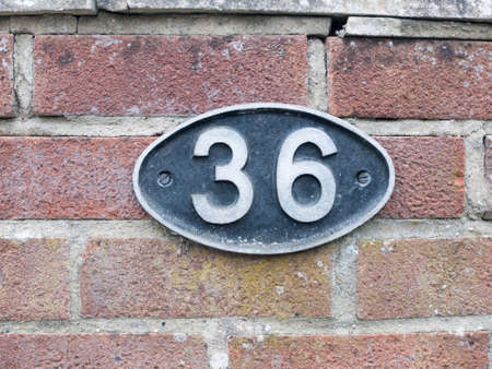 a number plate on a brick wall with 36 on it oval black sign stamp metal tag plate signの写真素材