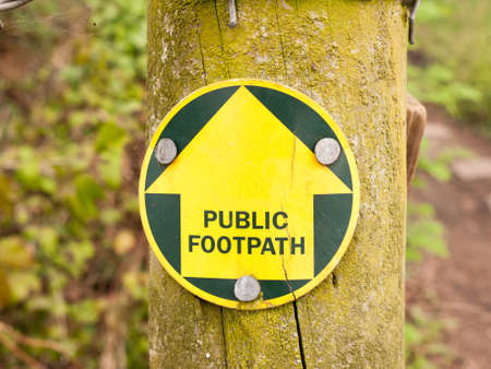 a public footpath sign in the forest leading the way on a trail in spring while walkingの写真素材