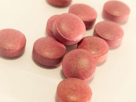red generic vitamin pills and tablets on a white background