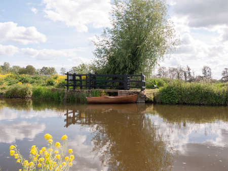 a wooden boat moored and parked on a river in the countryside of essex in the uk and england with no...