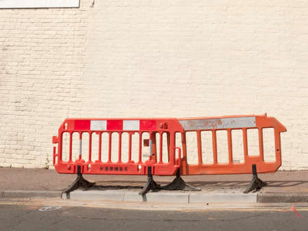 plastic red and orange construction fences on street path near roadの写真素材