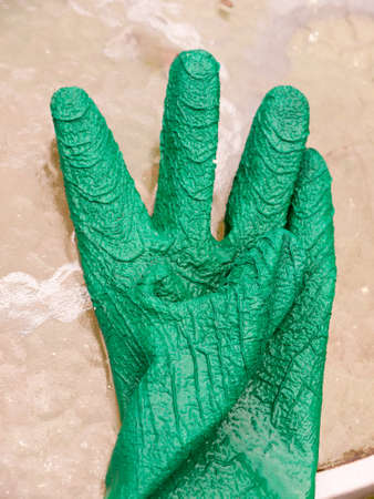 a wet single green gloves on glass table; Essex; UKの写真素材