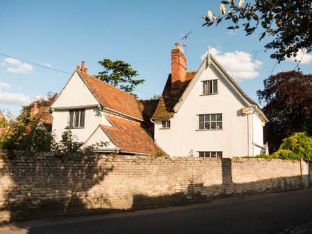 a white lovely cottage house in soft light and a brick wall and road in dedham; UKのeditorial素材