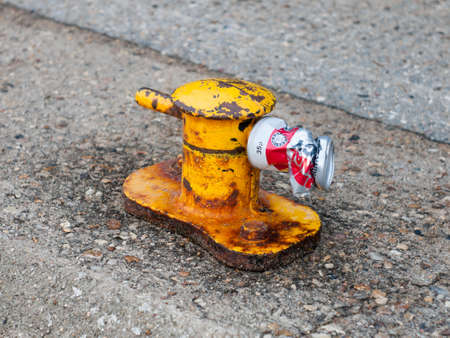 close up of crushed can on yellow marina port rope holderの写真素材