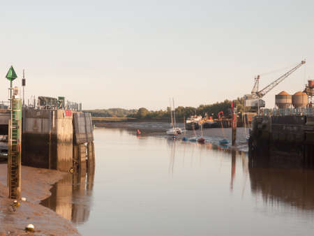 sunset light scene over dock gate open with moored boats river; England; Essexのeditorial素材