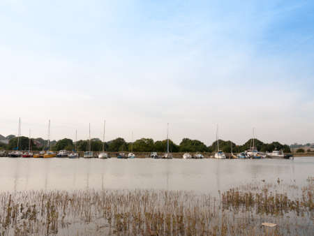 row of parked boats on river across the way; Essex; England; UKの写真素材