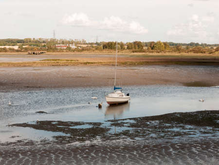 single white boat with mast parked in estuary river stream outside landscape; Essex; England; UKの写真素材