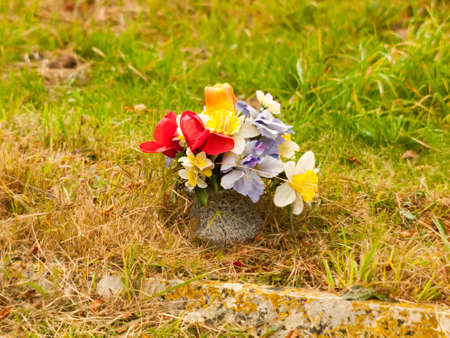 bunch of fake plastic flowers on grass grave; essex; england; ukの写真素材
