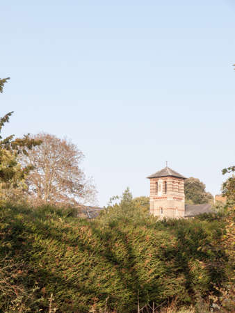 old stone tower in distance in sky behind hedge tree tops; essex; england; ukの写真素材