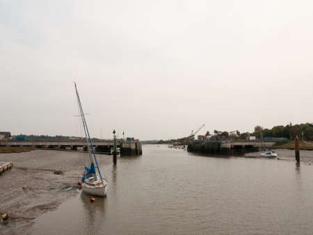 dock scene grey overcast day barrier open moored boats; essex; england; uk