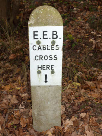 cables crossing stone sign post forest floor warning; essex; england; ukの写真素材
