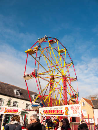red and yellow carousel wheel outside with people below blue sky christmas fair; essex; england; ukのeditorial素材