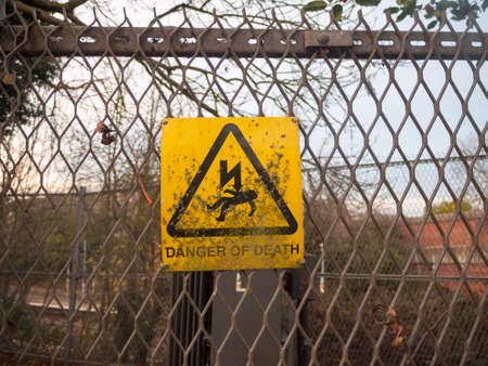 danger of death yellow rusty dirty unclean sign on metal fence lightning bolt; essex; england; ukの写真素材