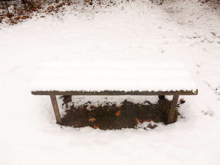 wooden covered public bench snow outside winter grass covered white; essex; england; ukの写真素材