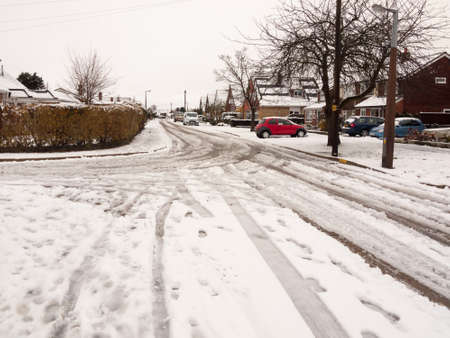 snow covered street road with tire tracks leading through village houses; essex; england; ukの写真素材