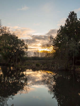 beautiful sun set autumn light sky over river trees reflections water surface; essex; england; uk