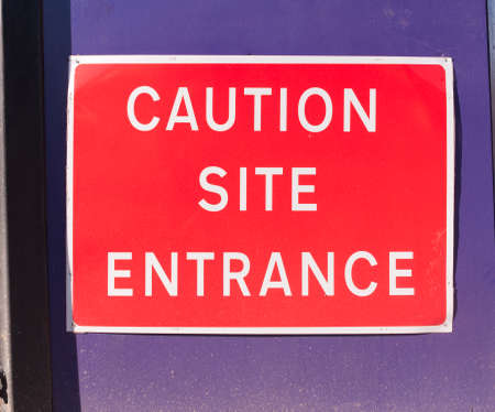 close up construction site sign red caution site entrance; essex; england; uk