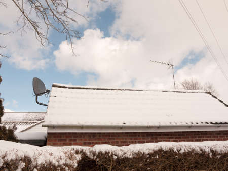snow covered roof outside with black satellite dish; essex; england; ukの写真素材