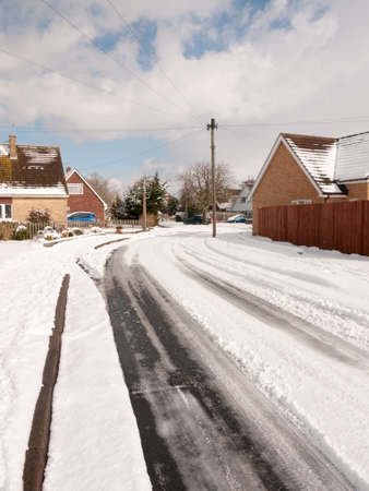 winter road through uk estate tracks no cars empty path snow; essex; england; ukの写真素材