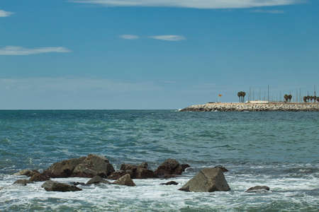 seascape with rocks in the foreground and breakwater in the backgroundの写真素材