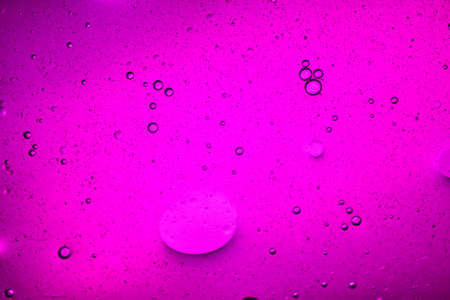 close-up view of a dark pink liquid background of moving bubblesの写真素材