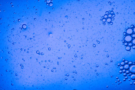 close-up view of a bright blue liquid background of moving bubblesの写真素材