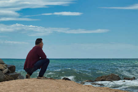 lonely man looking the horizon from the seashore on a sunny dayの写真素材