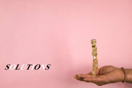 hand holding a stack of wooden blocks in balance with shapes and concept of solutions on a pink backgroundの写真素材
