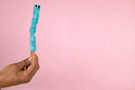 hand holding a blue stack of wooden blocks in balance on a pink backgroundの写真素材