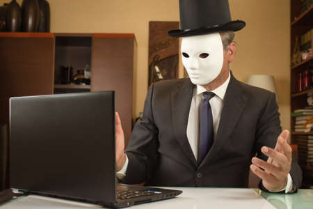 businessman camouflaged with a mask and hat telecommuting from home due to restrictionsの写真素材