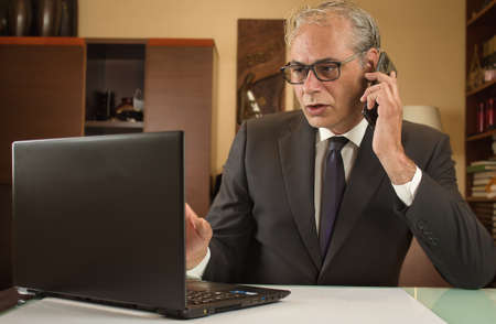 businessman teleworking from home with laptop and mobile due to restrictionsの写真素材