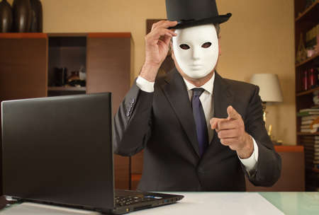 businessman disguised with a mask and hat telecommuting from home due to restrictionsの写真素材