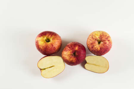 group of red apples and cut pieces with drops on white background viewed from above