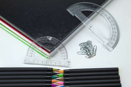 foreground of set of school tools with colored self-tips pens, clips, notebooks and ruler on white...