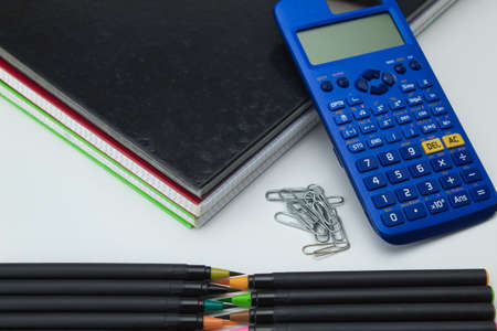 group of school tools with notebooks, markers, pens, clips and calculator ready for back to school...