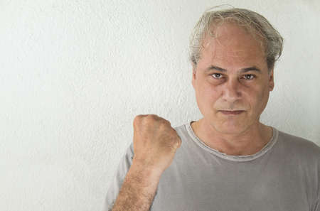 mature man with gray hair and raised fist in victory sign on white backgroundの写真素材