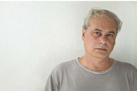 mature man looking straight ahead at camera on white backgroundの写真素材