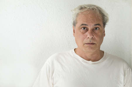 portrait of mature man with gray hair in white shirt on a white backgroundの写真素材