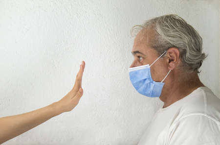a hand of girl stopping a mature man with mask on white background with copy spaceの写真素材