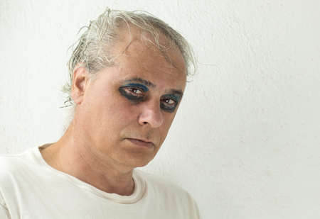 close-up of a mature man with gray hair and painted eyes on a white backgroundの写真素材