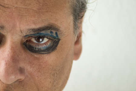 close-up of a mature man with gray hair and painted eyes on a white backgroundの写真素材