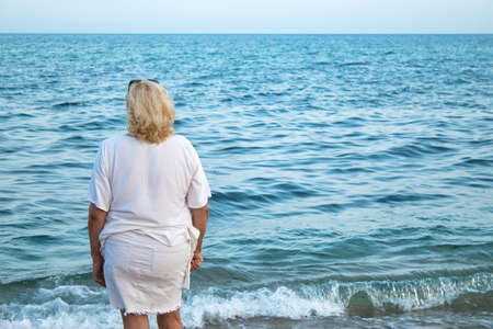 mature woman enjoying on the seashore in a white dressの写真素材