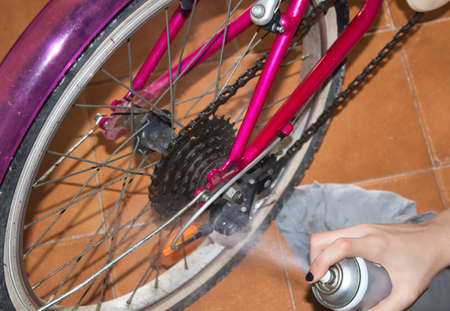 view of a hands of a girl cleaning her bike with a rag and sprayの写真素材